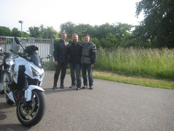 Links ein Motorrad und drei Mitfahrer die sich im Bild positionieren