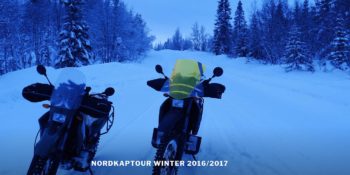Zwei Motorräder auf einer verschneiten Straße im Dämmerlicht
