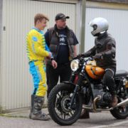 Drei Personen unterhalten sich eine sitzt auf dem Motorrad