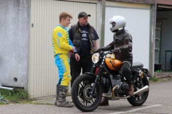 Drei Personen unterhalten sich eine sitzt auf dem Motorrad