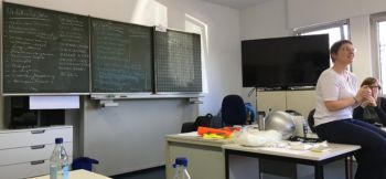 Beim erste Hilfe Kurs. Vor einer beschriebenen Tafel liegen Utensilien und die Referentin spricht.